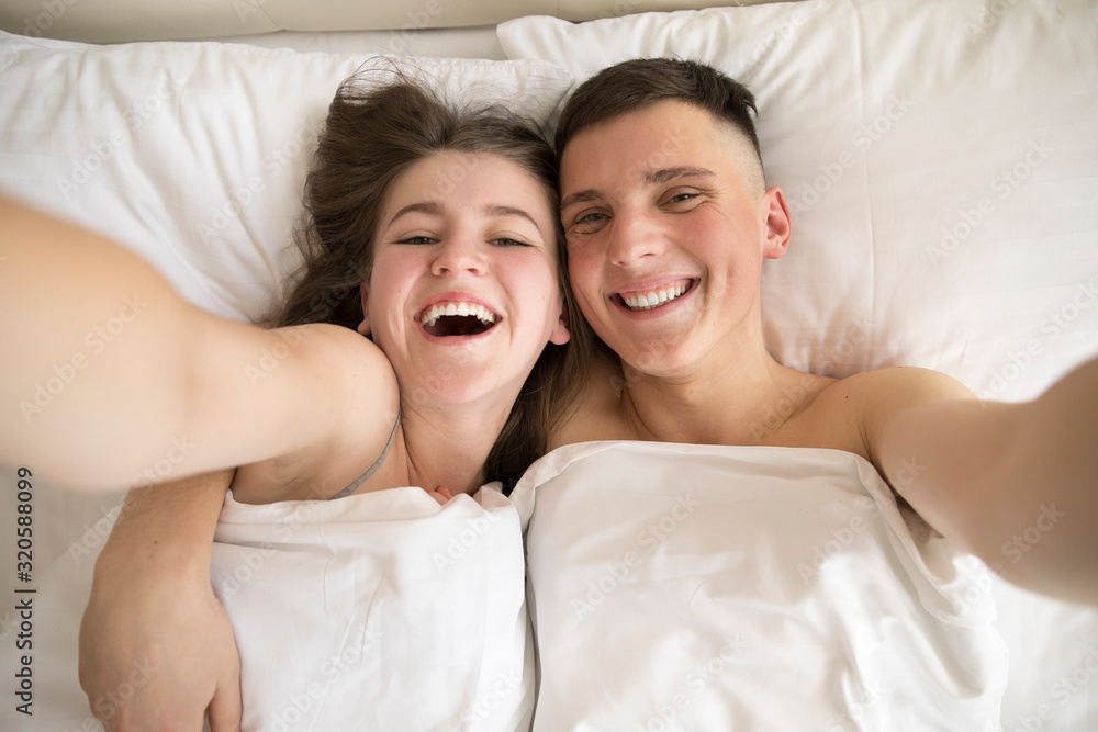 Top view of smiling couple taking selfie in bed Top view of smiling couple taking selfie in bed