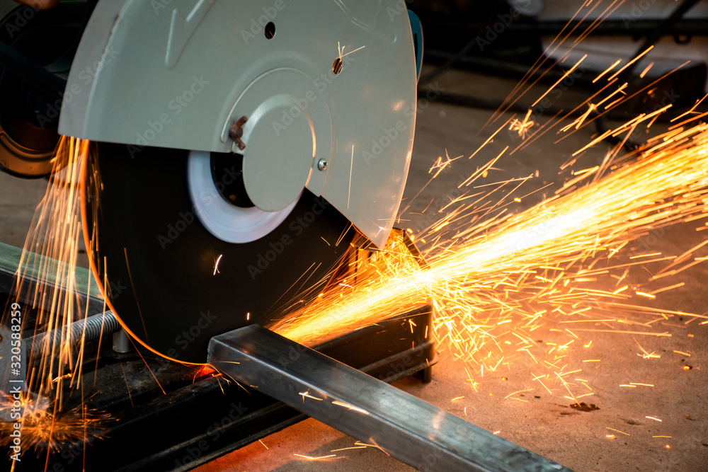 Steel cutter grinder are cutting iron pipe with bright sparks. - obrazy, fototapety, plakaty 