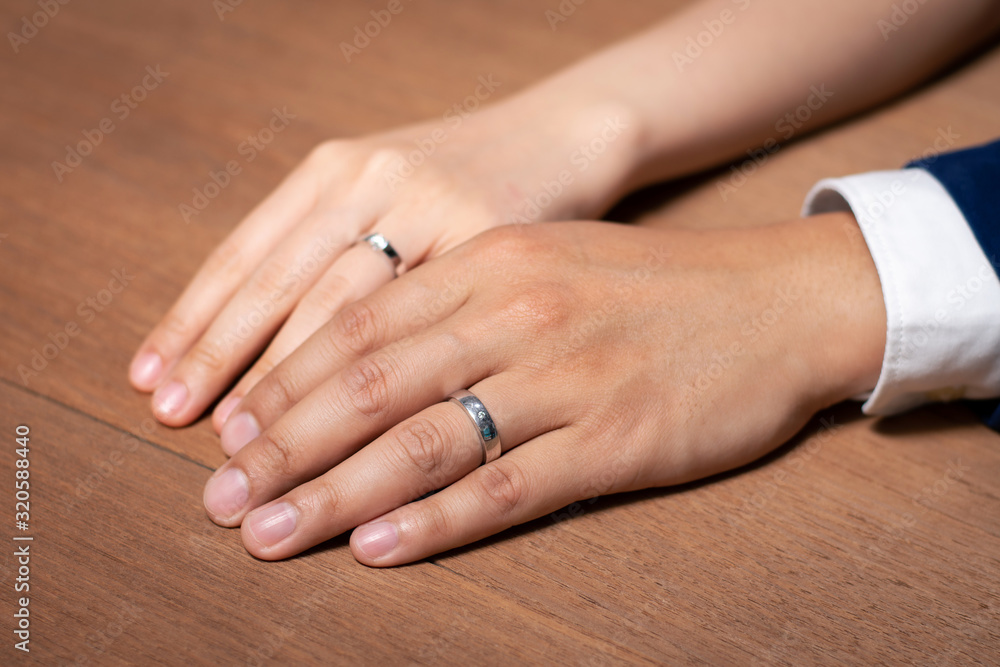 Bride and groom holding hands with wedding ring on wooden table. Bride and groom holding hands with wedding ring on wooden table.