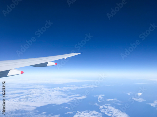 Wing of the plane on blue sky with white clouds  High angle view of the plane with clouds and sky background