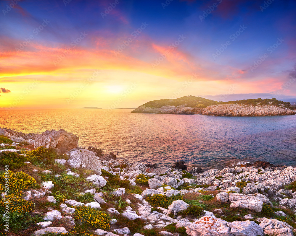 Amazing sunset view with multicolored clouds. Incredibly romantic sunrise on Voidokilia beach, Ionian Sea, Pilos town location, Greece, Europe. View of the ocean through the rocky shore