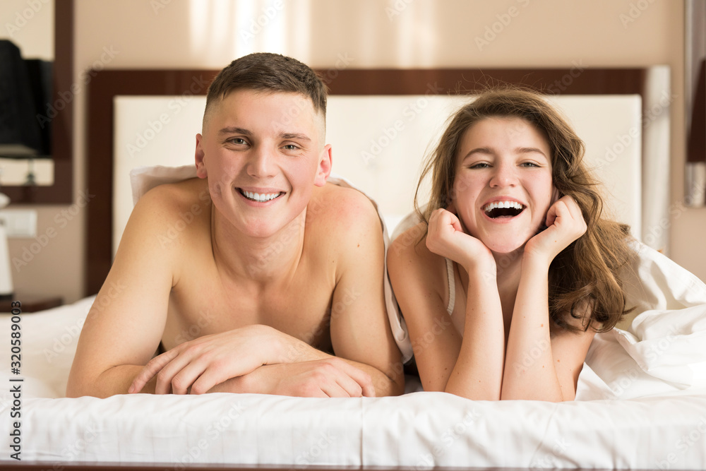 Front view of smiling sexy couple lying on bed