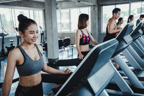 Woman running on treadmill with the friends.