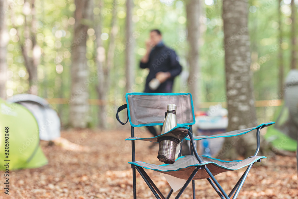 thermos container with tea or coffee for camping in the forest on the fishing chair or relaxing in the nature for an idyllic get away thermos container with tea or coffee for camping in the forest on the fishing chair or relaxing in the nature for an idyllic get away