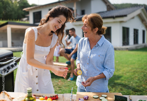 Portrait of multigeneration family outdoors on garden barbecue, grilling. photo