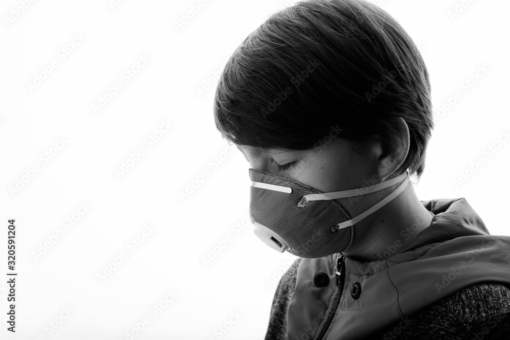 Portrait of young boy in protective respirator with closed eyes. Child wearing medical mask. Free space for text. White background. Healthcare, personal protection, virus, air pollution concept. 