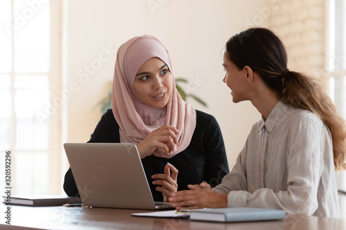 Multicultural businesswomen brainstorm cooperating at office meeting