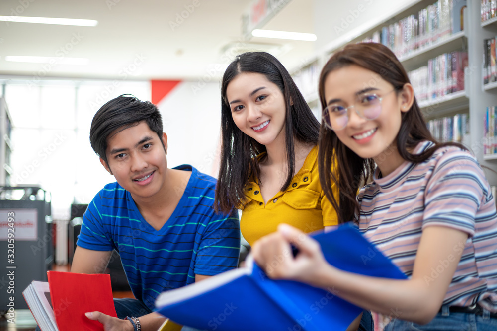 Group Asian Students Smile and reading book and using notebook for helps to share ideas in the work and project. And also review the book before the exam Group Asian Students Smile and reading book and using notebook for helps to share ideas in the work and project. And also review the book before the exam