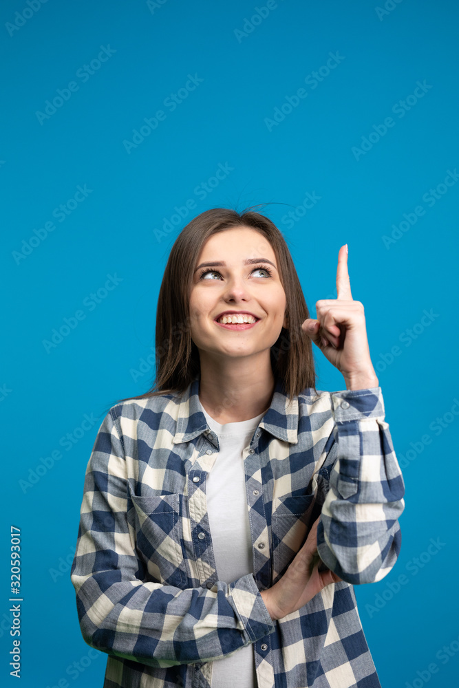 Smiling girl showing idea sign isolated on blue background