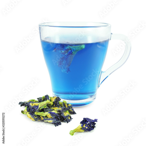 Bright Butterfly pea flower tea (Thai Blue Tea) in glass cup next to dried buds isolated on white background 