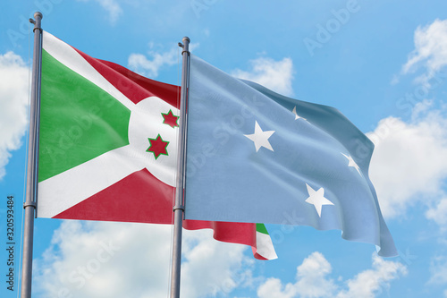 Micronesia and Burundi flags waving in the wind against white cloudy blue sky together. Diplomacy concept, international relations.