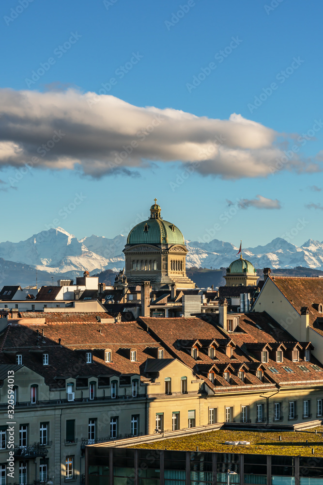 Blick über die Berner Altstadt auf das Bundeshaus im Abendlicht vor Bergkulisse – Bern, Schweiz