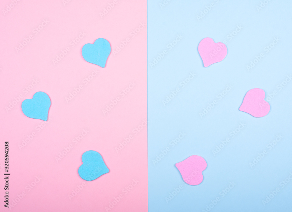 Blue and pink paper hearts on a split pink and blue background (top view, minimalist style)