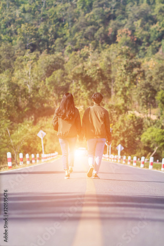 Smooth Focus,Valentine couples walking hand in hand, along the road with Golden light coming straight from the front and promised to take care of each other with love and caring. Lovers love concept.