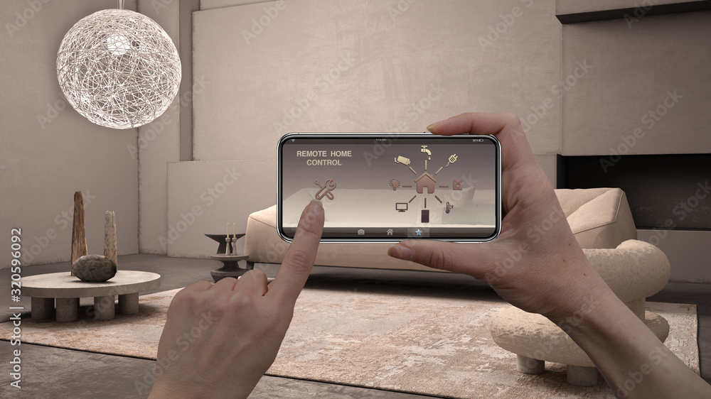 Remote home control system on a digital smart phone tablet. Device with app icons. Interior of grunge living room with plaster walls, fireplace in the background, architecture design Remote home control system on a digital smart phone tablet. Device with app icons. Interior of grunge living room with plaster walls, fireplace in the background, architecture design