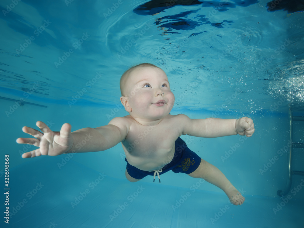 Little boy learns to dive underwater in a swimming pool
