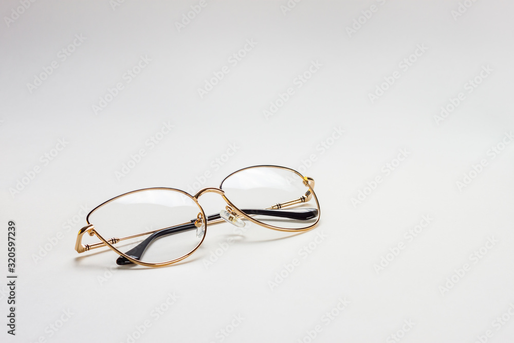 The perspective view of a golden female medical eyeglasses with folded temples on a white background The perspective view of a golden female medical eyeglasses with folded temples on a white background