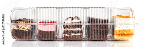 Assorted Tiramisu cakes in a closed transparent plastic box isolated on white background. Front view