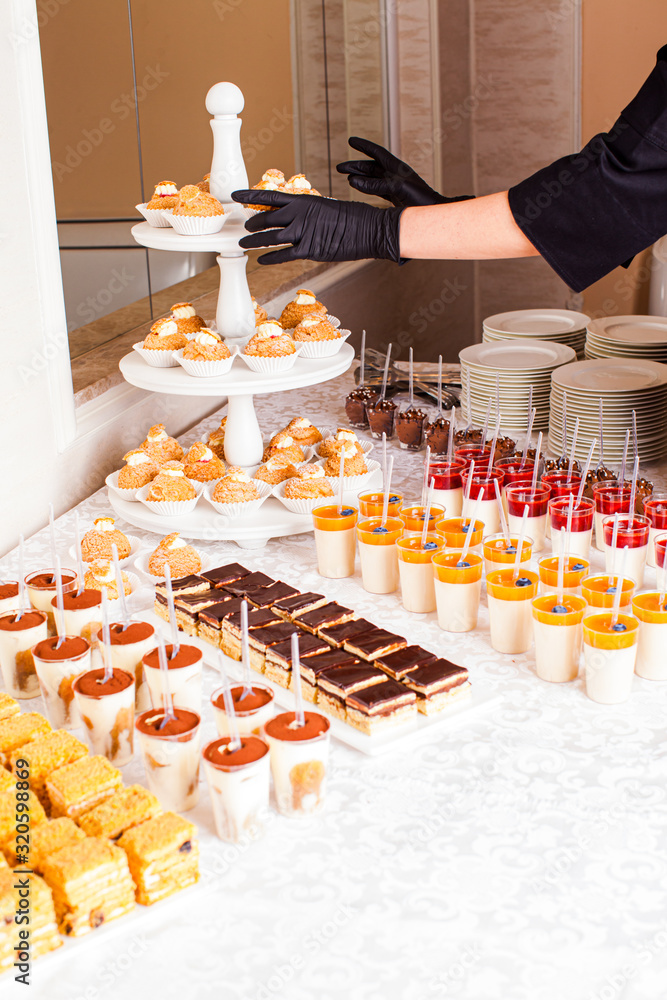 Catering waitress service. Woman at restaurant servicing dessert table