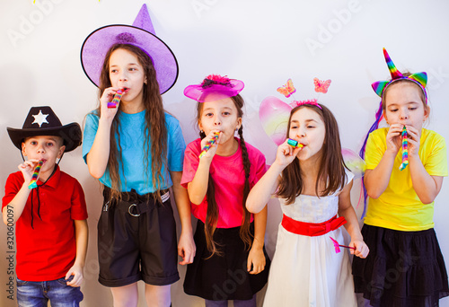 Adorable kids having fun at birthday party. Friends blowing whistles and enjoying party