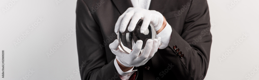 cropped view of professional magician holding magic ball, isolated on grey, panoramic shot