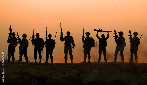 group of military silhouettes on sunset sky background standing