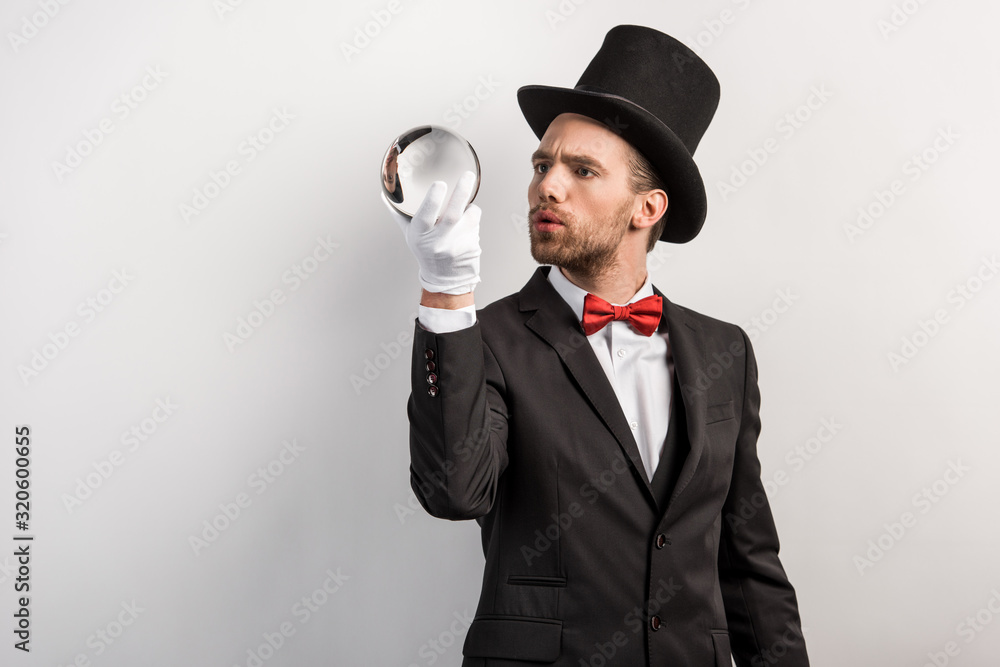 interested professional magician holding magic ball, isolated on grey interested professional magician holding magic ball, isolated on grey
