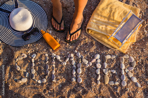 Fototapeta Naklejka Na Ścianę i Meble -  Top view of the sandy beach by the sea, beach items are laid out on the sand. The word SUMMER is laid out of stone