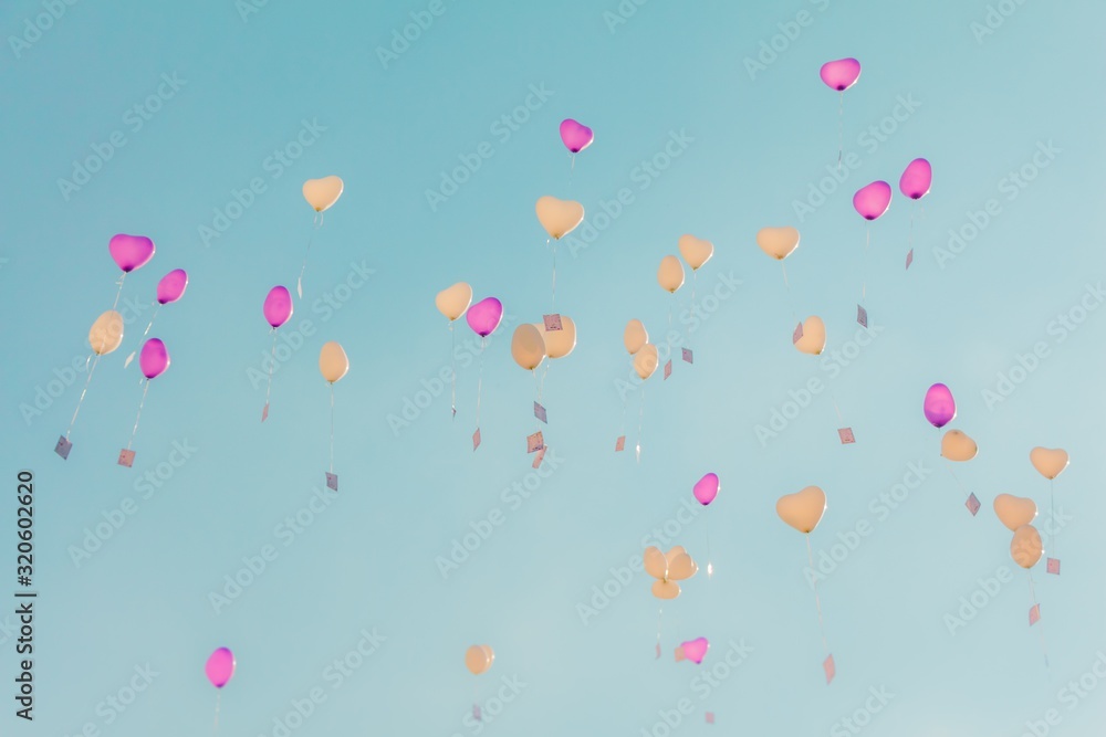 Heart love balloons fly into turquoise sky with ceremony wishes. Romantic symbol of future partnership. Group of beautiful heart ballons with congratulations cards at wedding party or valentines day