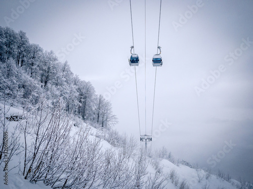 Winter Mountain landscape at the Rosa Khutor ski resort in Sochi, Russia. Cable car cabin over pine trees in the snow