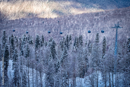 Winter Mountain landscape at the Rosa Khutor ski resort in Sochi, Russia. Cable car cabin over pine trees in the snow