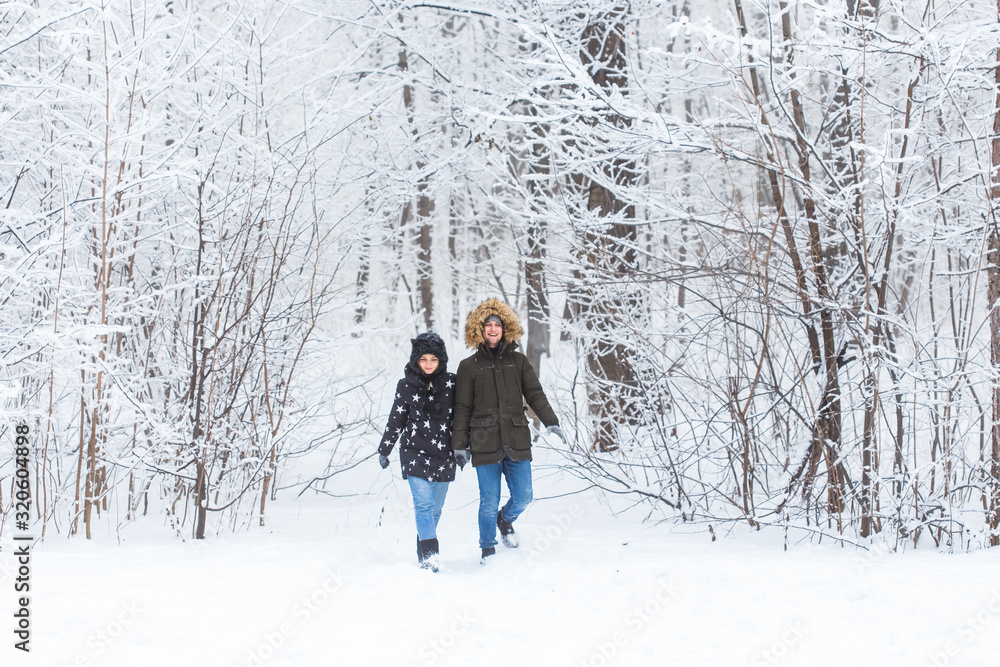 Young couple walking in a snowy park. Winter season. Young couple walking in a snowy park. Winter season.