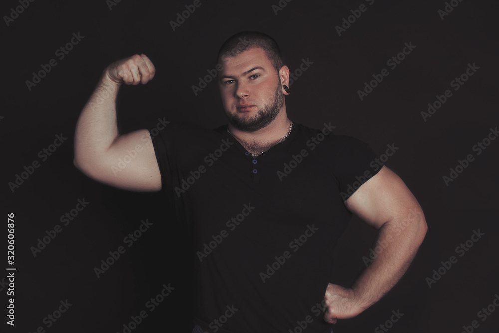 sports guy stands on a black background and shows biceps