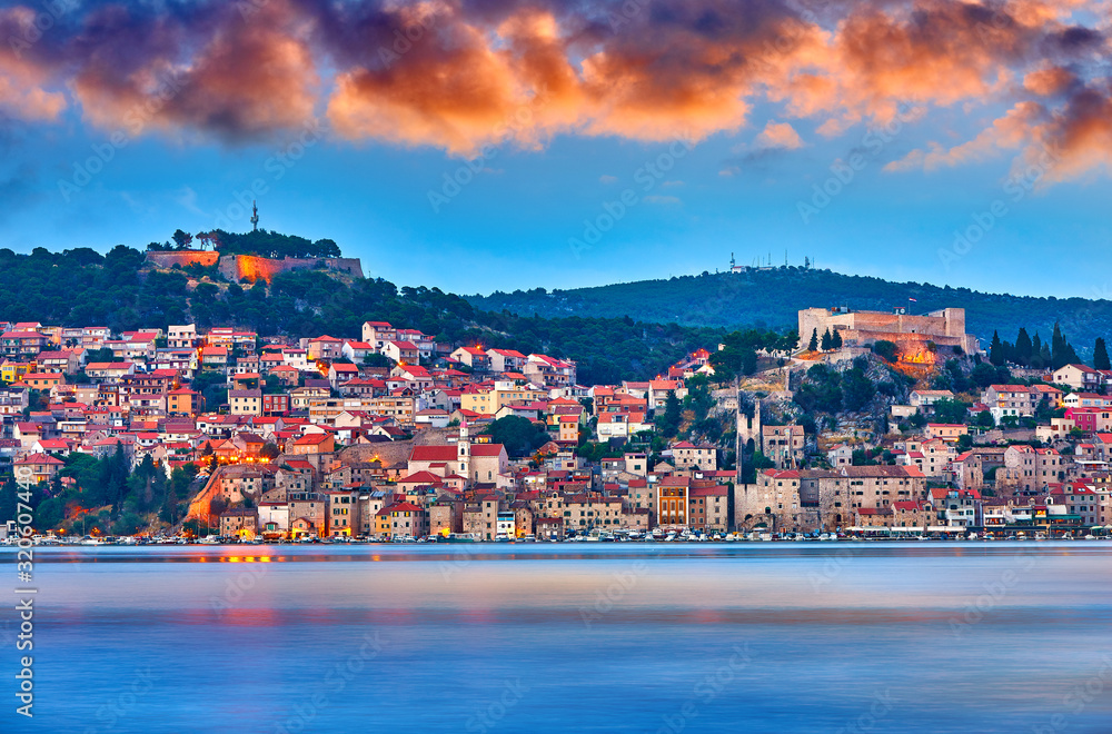 Large panorama of Unesco heritage historic town of Sibenik on Adriatic sea, Dalmatia, Croatia. Shot from the sea, harbor, waterfront and cathedral in front. Dramatic red sky at night. Evening city..