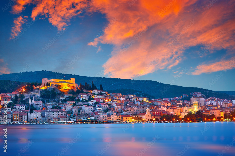 Large panorama of Unesco heritage historic town of Sibenik on Adriatic sea, Dalmatia, Croatia. Shot from the sea, harbor, waterfront and cathedral in front. Dramatic red sky at night..