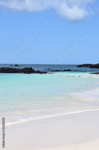 Fototapeta Naklejka Na Ścianę i Meble -  Sandy tropical beach and blue turquoise ocean water under blue sky and lava stones