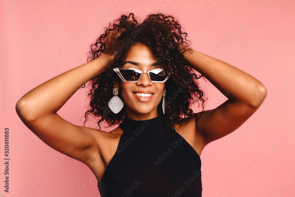 Beautiful african american girl with an afro hairstyle smiling. Portrait of happy young black woman laughing against pink wall.Blissful lovable woman with african hairstyle laughing indoor