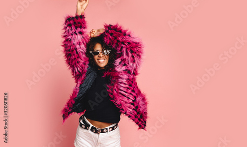 Black woman in a black faux fur jacket, Close up fashion portrait of crazy hipster African girl with funny curly hairstyle and vivid faux fur coat, urban trendy style. Horizontal.copy space