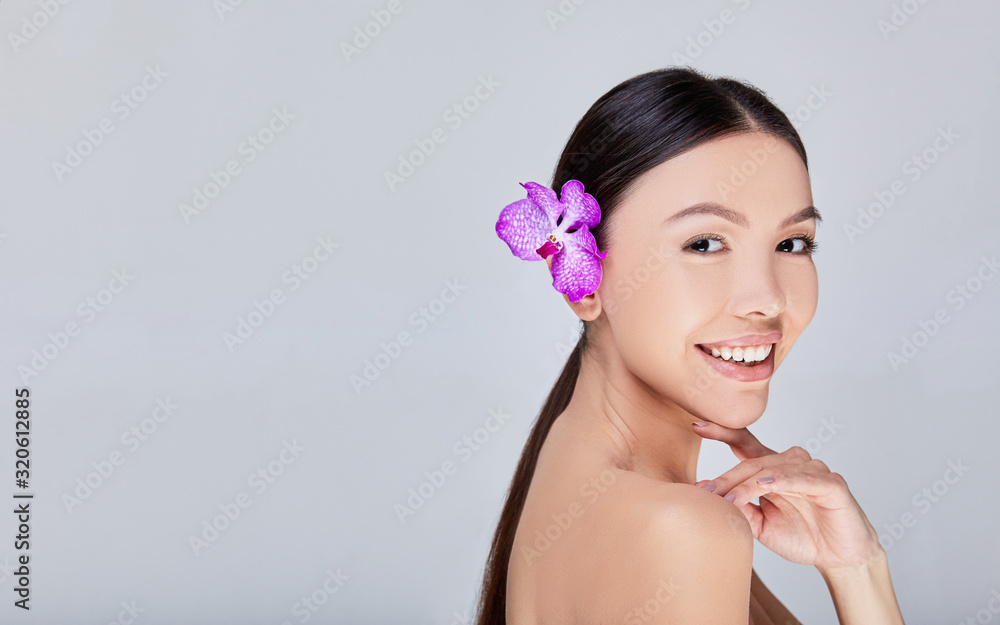 Sweet girl smiles in frame broadly with orchid Sweet girl smiles in frame broadly with orchid