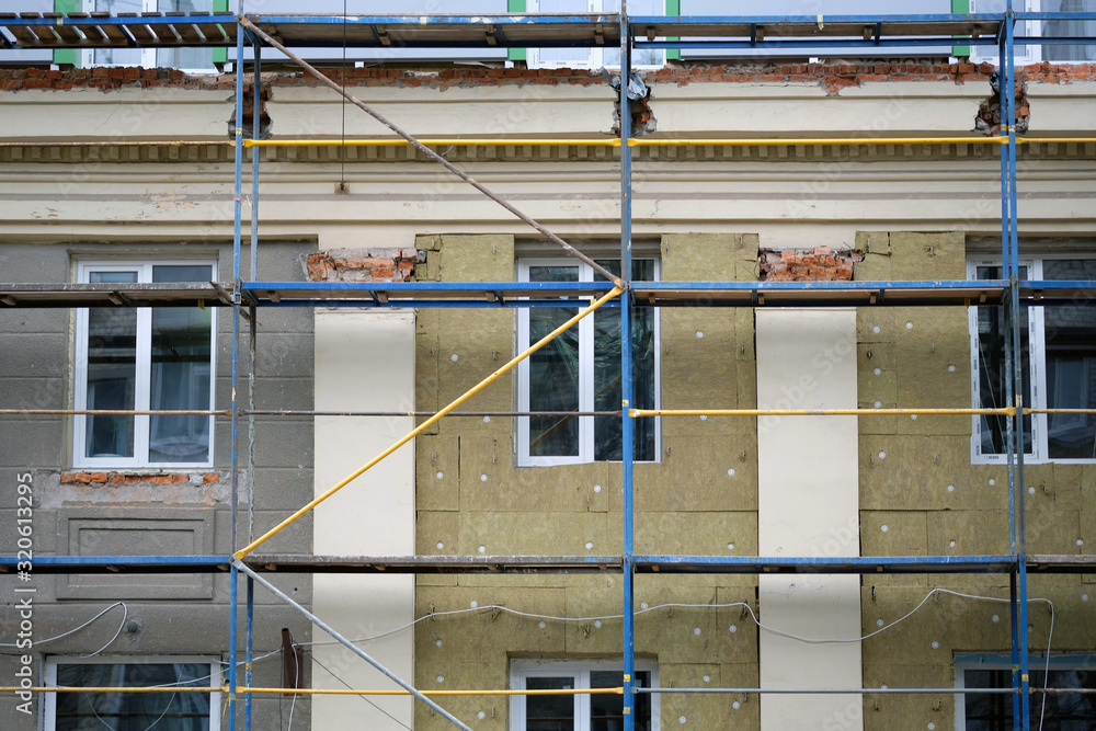 Outside repair and renovation of a apartment house. Close up of flats being built with scaffolding surround. Metal beams vast scaffolding providing platforms to support the stage structure