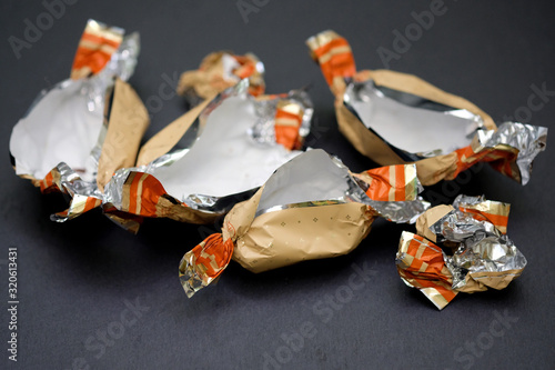 Empty candy wrappers close-up. Packages of chocolates on a black background. Weight gain concept, living hard without sweets.