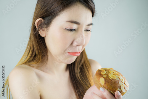 portrait of beautiful asian woman dicision to stop eating cake. isolated on white background. photo