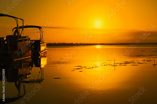Sunrise over lake Bacalar with two tour boats in the foreground