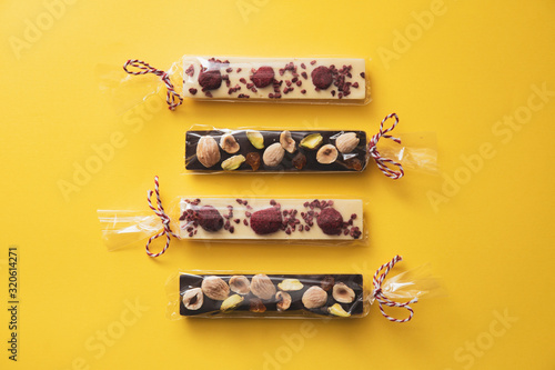 Four artisan chocolate bars with nuts wrapped in plastic with a lace as a gift © xfgiro