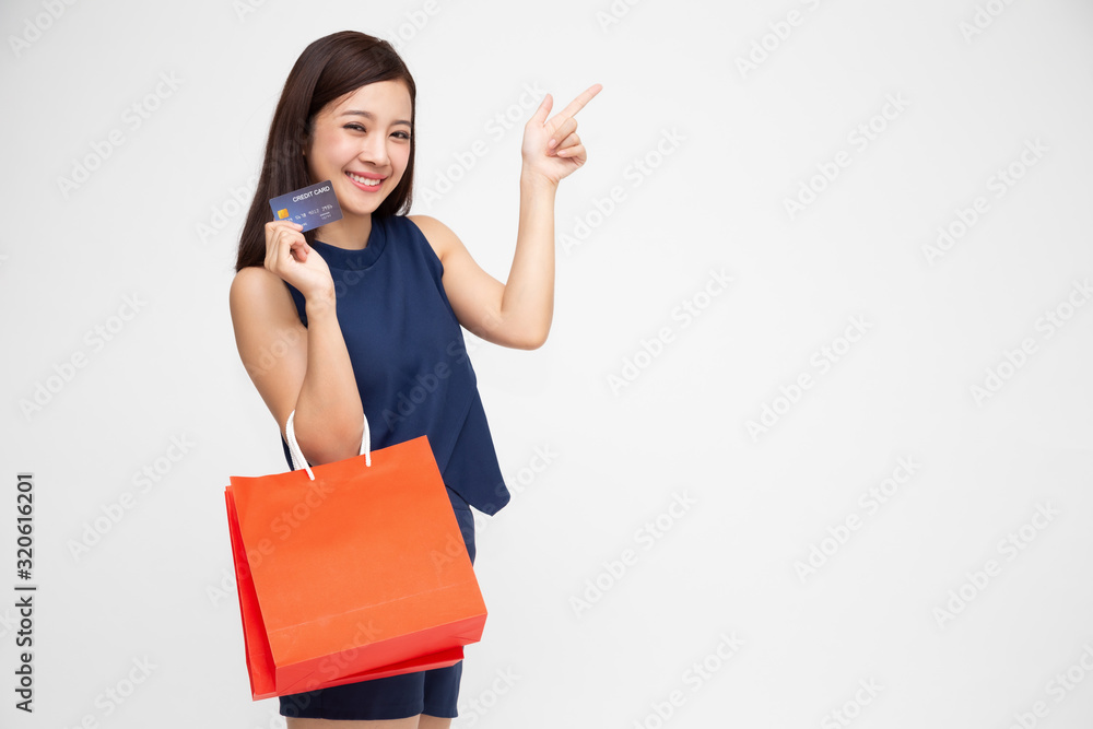 Happy asian beautiful girl with shopping bags and credit card doing shopping and pointing finger to blank copy space Happy asian beautiful girl with shopping bags and credit card doing shopping and pointing finger to blank copy space