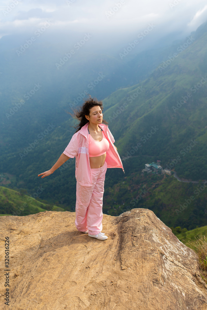 Naklejka premium Girl enjoys a mountain view while standing on a cliff