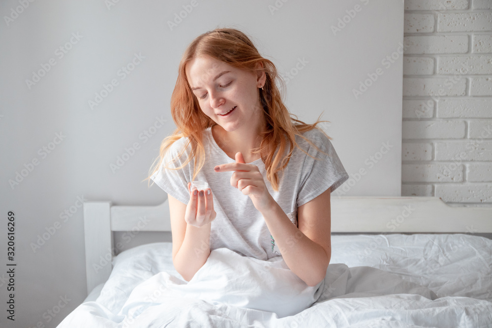 Woman caring of her beautiful skin on the face sitting on the bed. Skin care and beauty concept Woman caring of her beautiful skin on the face sitting on the bed. Skin care and beauty concept