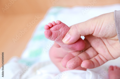 Newborn s legs are small in the hands of parents