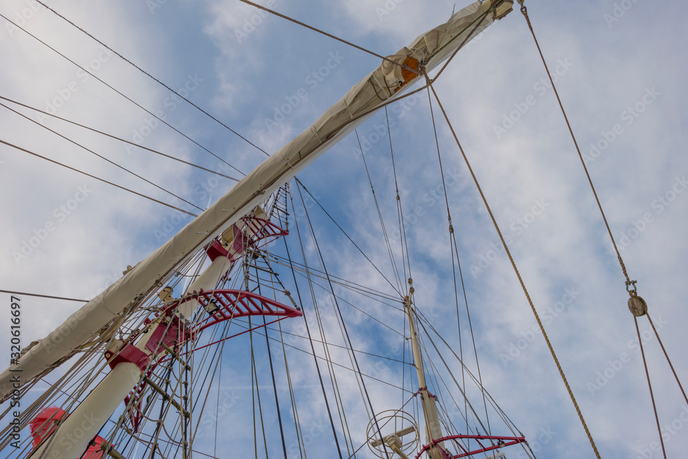Obraz premium Rigging of a tall ship below a blue cloudy sky in sunlight in winter