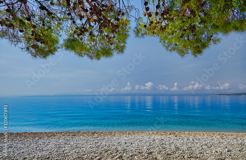 Amazing seascape of Adriatic sea. Colorful summer view of small Brela beach Croatia, Europe. Croatian coast with clear water and pine trees around. Tropical viewpoint for design postcard.